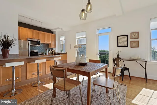 a kitchen with stainless steel appliances granite countertop a stove a refrigerator a kitchen island with a dining table and chairs