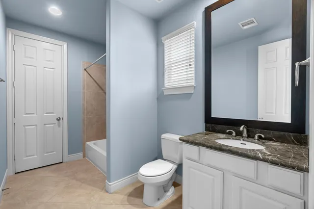 a bathroom with a granite countertop toilet sink and mirror