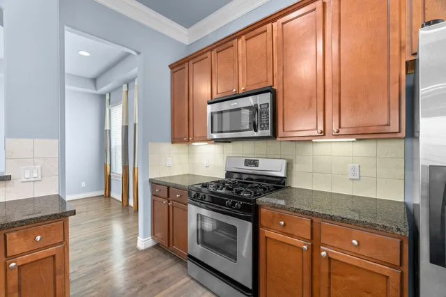 a kitchen with granite countertop wooden cabinets stainless steel appliances and a window