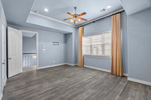 an empty room with wooden floor and a ceiling fan