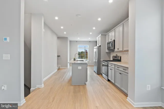 a large kitchen with cabinets wooden floor and stainless steel appliances