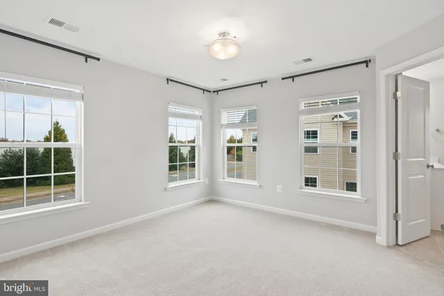 a view of an empty room with a window and cabinet area