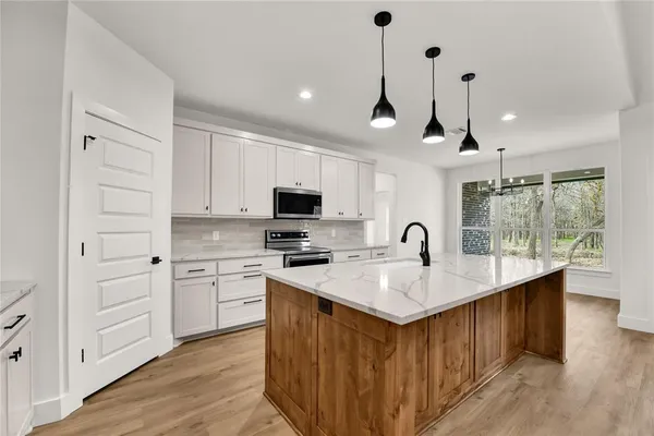 a kitchen with stainless steel appliances granite countertop a sink a stove and a wooden floors