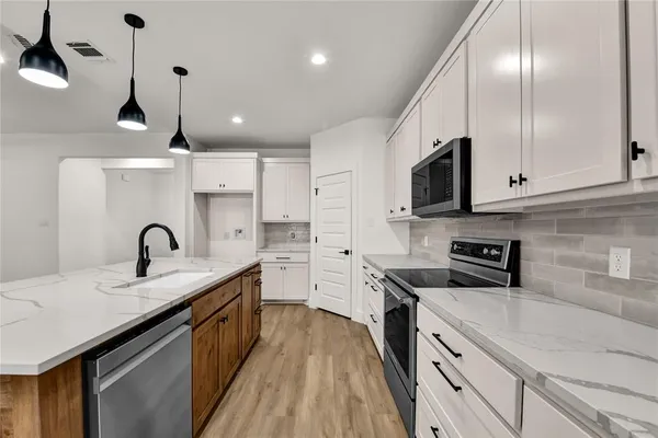 a kitchen with stainless steel appliances granite countertop a sink a stove and a refrigerator