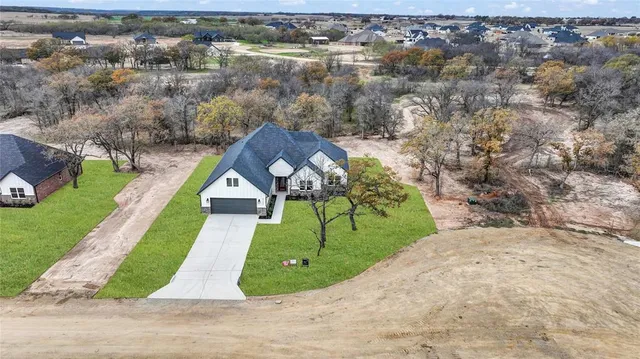 an aerial view of a house with a yard and lake view