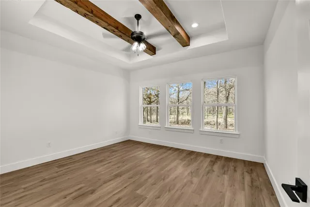 an empty room with wooden floor fan and windows