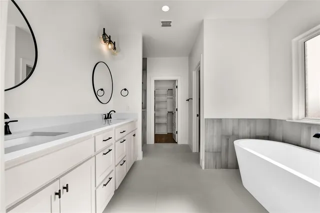 a bathroom with a tub a double vanity sink and a mirror