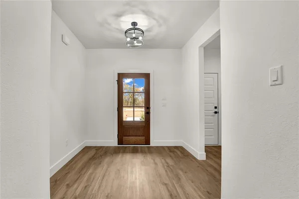 an empty room with wooden floor chandelier and windows