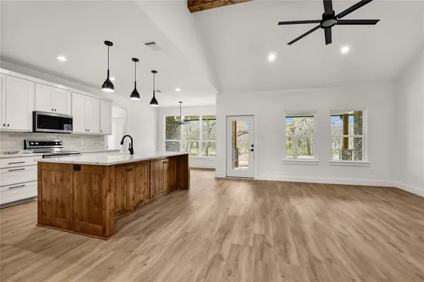 a large kitchen with stainless steel appliances granite countertop a stove a sink and a microwave