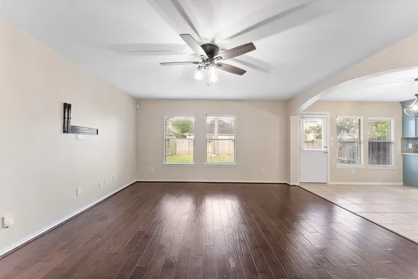 a view of an empty room with wooden floor and a window