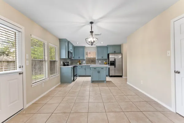a large kitchen with granite countertop a stove a sink and a refrigerator