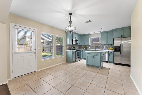 a kitchen with stainless steel appliances granite countertop a sink a stove a refrigerator cabinets and a window