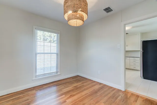 an empty room with wooden floor windows and entrance