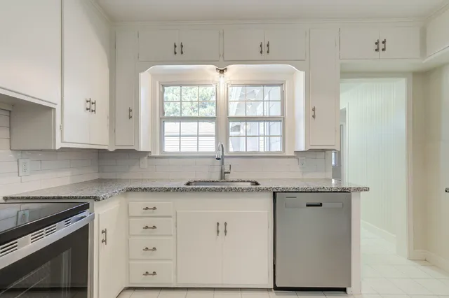 a kitchen with granite countertop white cabinets and white stainless steel appliances