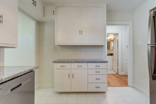 a kitchen with granite countertop white cabinets and white appliances