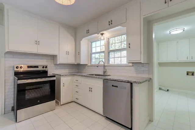 a kitchen with granite countertop white cabinets stainless steel appliances a sink and a window