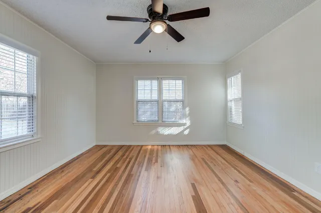 a view of empty room with wooden floor and fan