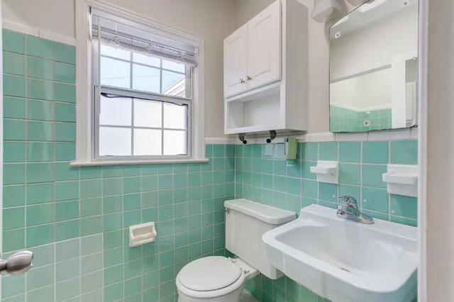 a bathroom with a sink a toilet a mirror and window