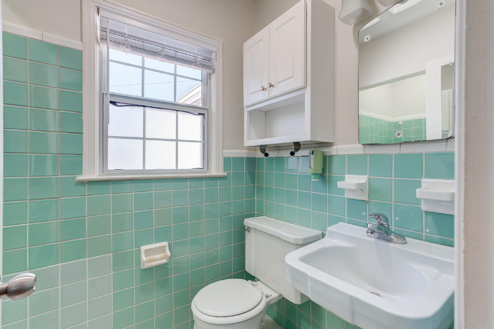2710 27th Street Lubbock, TX 79410 - Photo 32 of 38 a bathroom with a sink a toilet a mirror and window