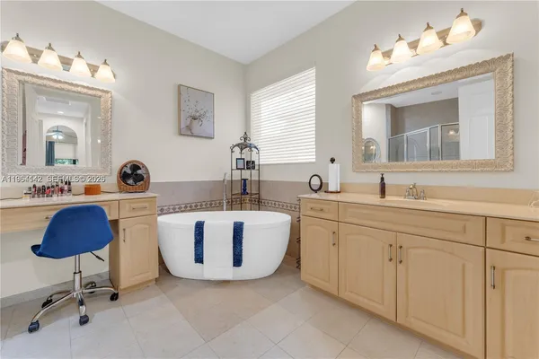 a bathroom with a double vanity sink a mirror a bathtub and a window