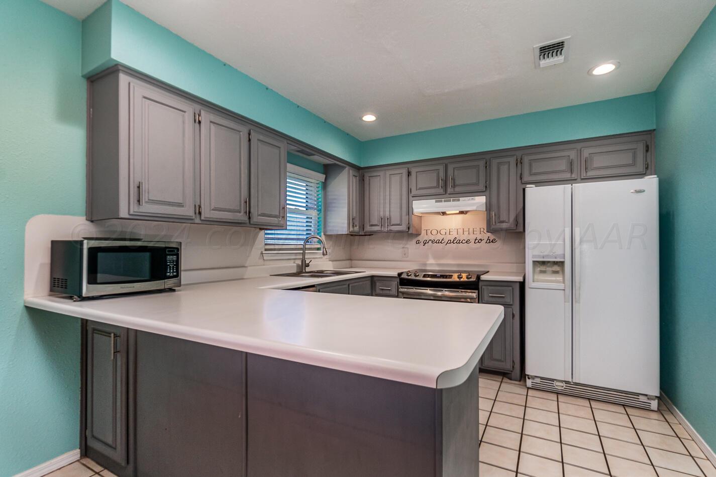 8012 Simpson Drive Amarillo, TX 79121 - Photo 9 of 28 a kitchen with stainless steel appliances a sink a stove a refrigerator a microwave and cabinets