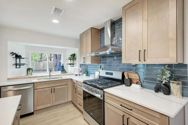 a large kitchen with a counter space a sink appliances and living room view
