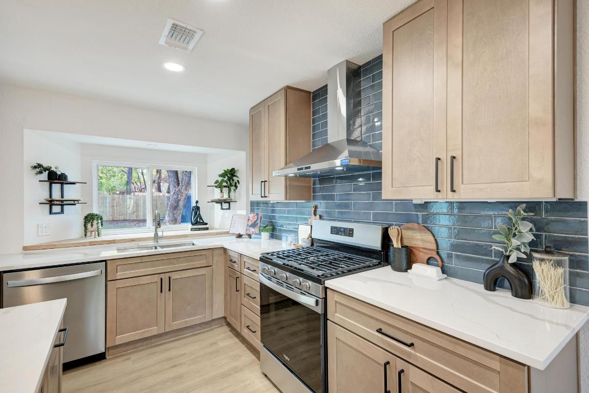 5106 Regency Drive Austin, TX 78724 - Photo 14 of 37 a kitchen with a sink dishwasher a stove and white cabinets with wooden floor