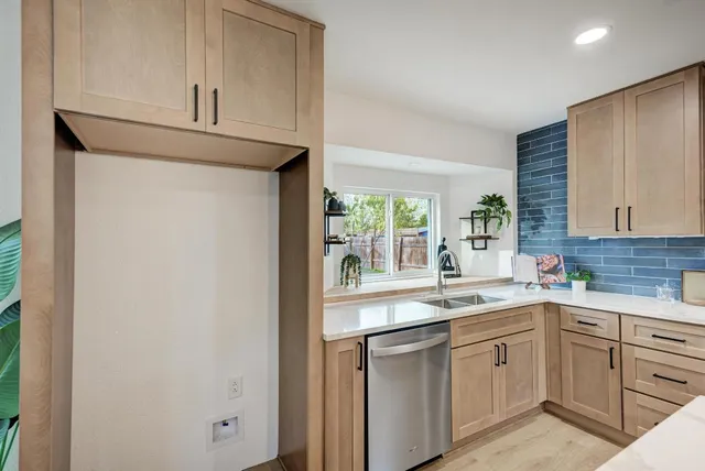 a kitchen with a sink dishwasher a stove and white cabinets with wooden floor