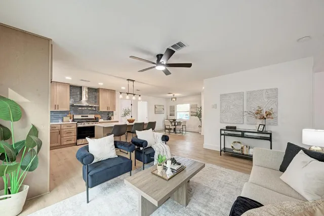 a living room with furniture kitchen view and a chandelier
