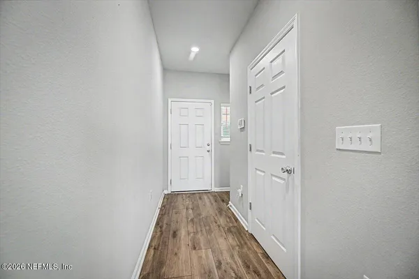 a view of an empty room with wooden floor and a ceiling fan