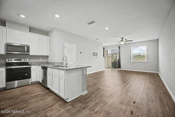 an empty room with chandelier fan and windows