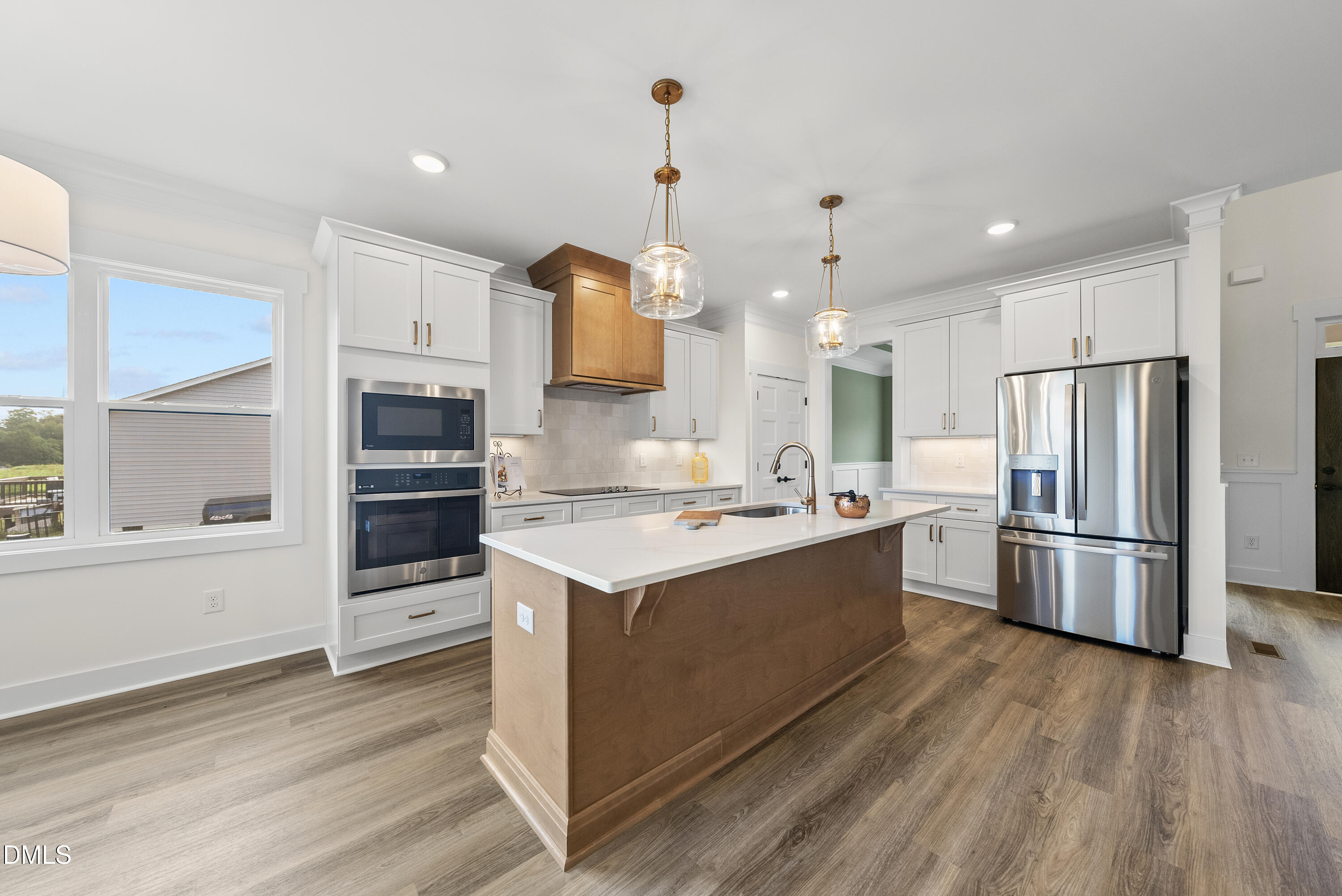 6786 Fire Tower Road Spring Hope, NC 27882 - Photo 11 of 30 a large kitchen with stainless steel appliances a stove a refrigerator and white cabinets with wooden floors
