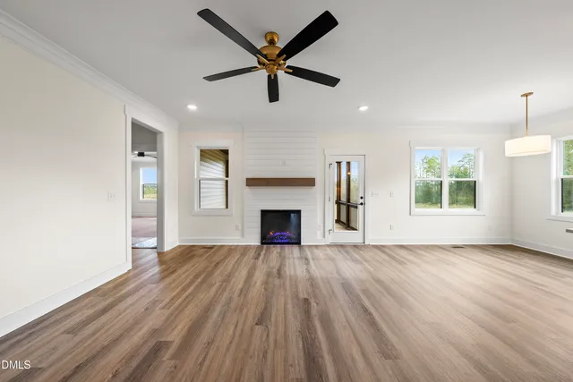 a view of empty room with wooden floor fireplace and a window