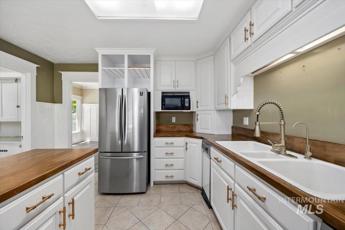 813 7th Street Rupert, ID 83350 - Photo 21 of 48 Kitchen featuring white cabinetry with gold-tone hardware, wood-finish countertops, and a double basin sink with a gooseneck faucet