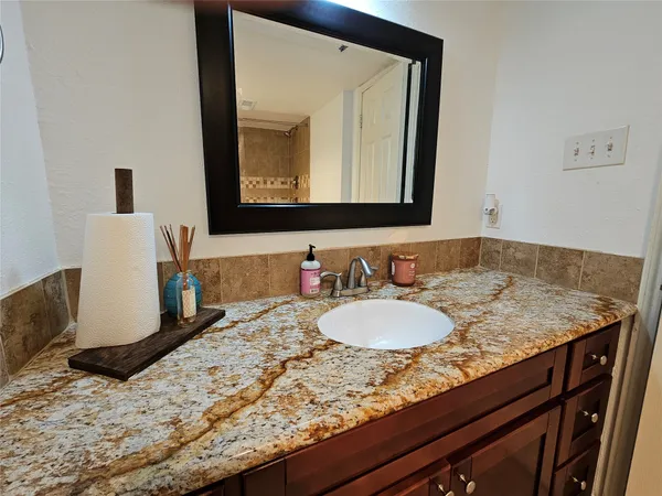 a bathroom with a granite countertop sink and a mirror