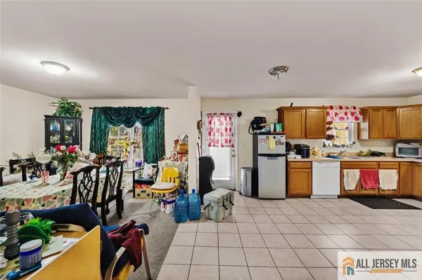 a room with lots of white furniture and open kitchen view