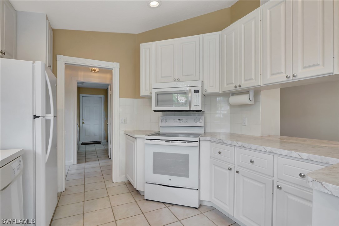 5682 Eleuthera Way Naples, FL 34119 - Photo 18 of 47 a kitchen with white cabinets and white appliances