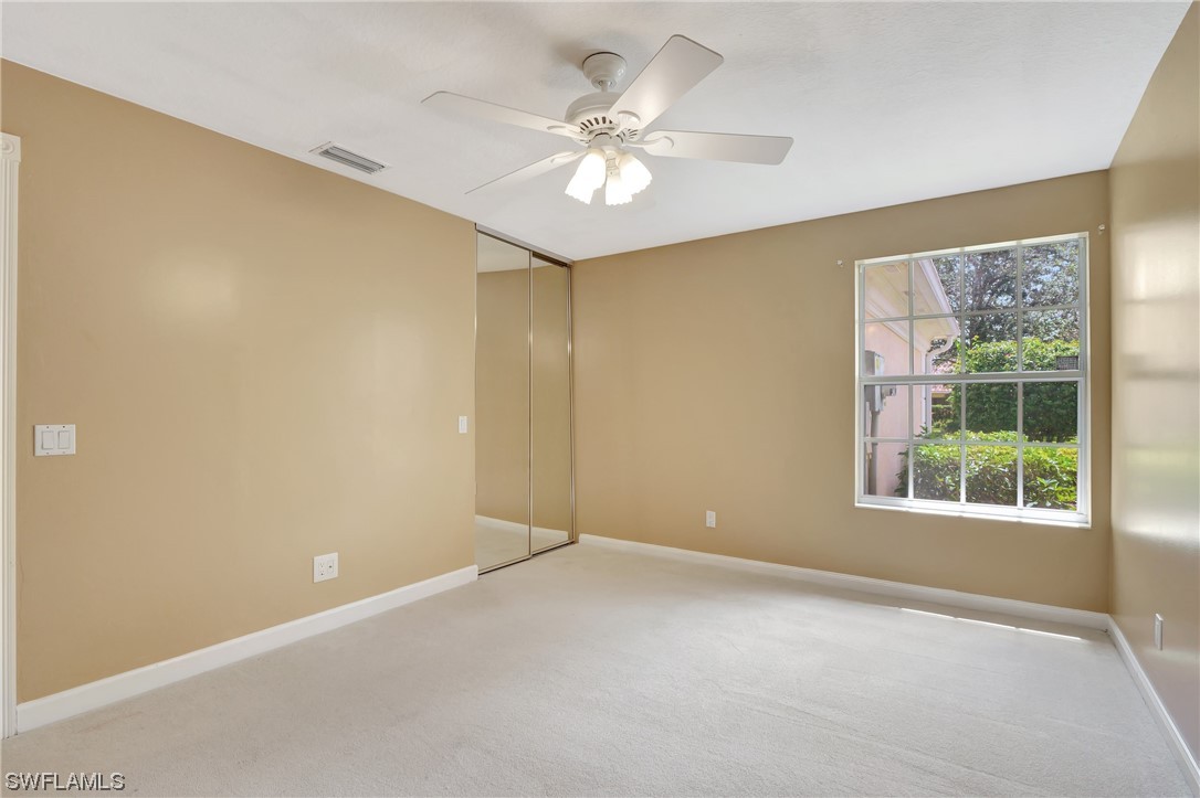 5682 Eleuthera Way Naples, FL 34119 - Photo 6 of 47 an empty room with a chandelier fan and windows