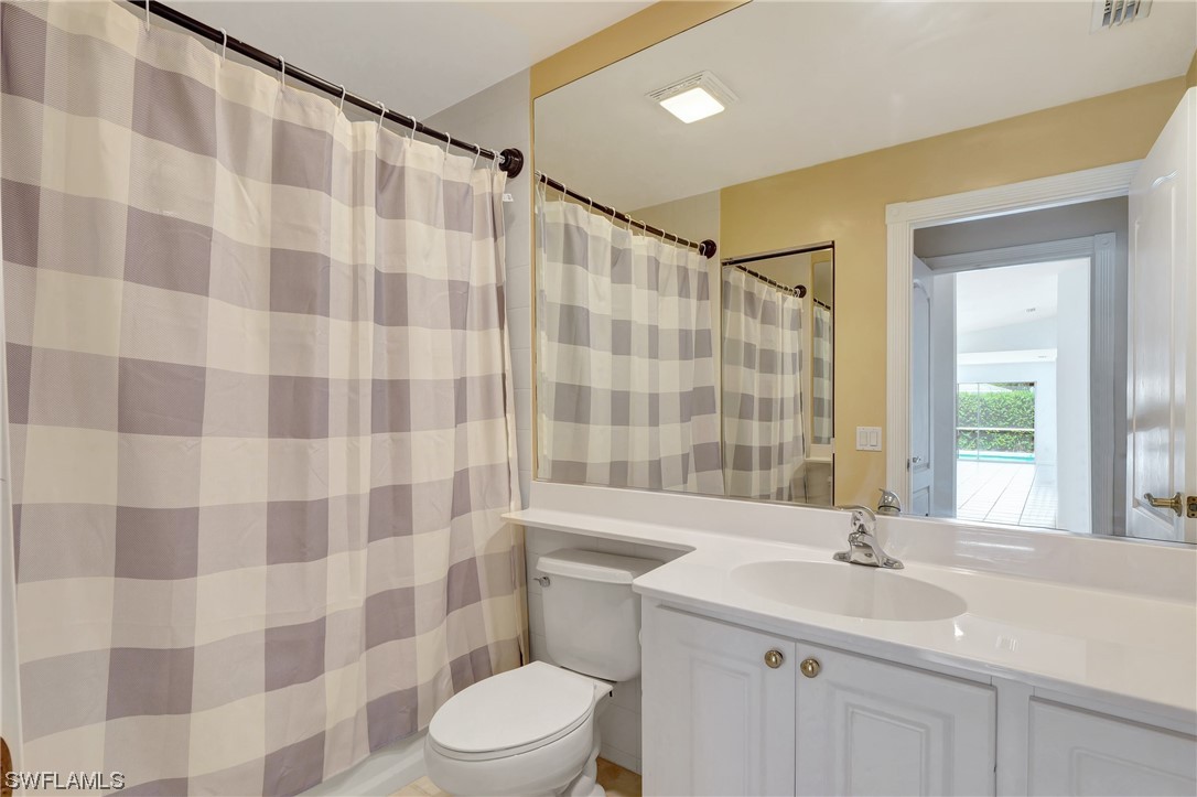 5682 Eleuthera Way Naples, FL 34119 - Photo 8 of 47 a bathroom with a sink a toilet a mirror and shower curtain