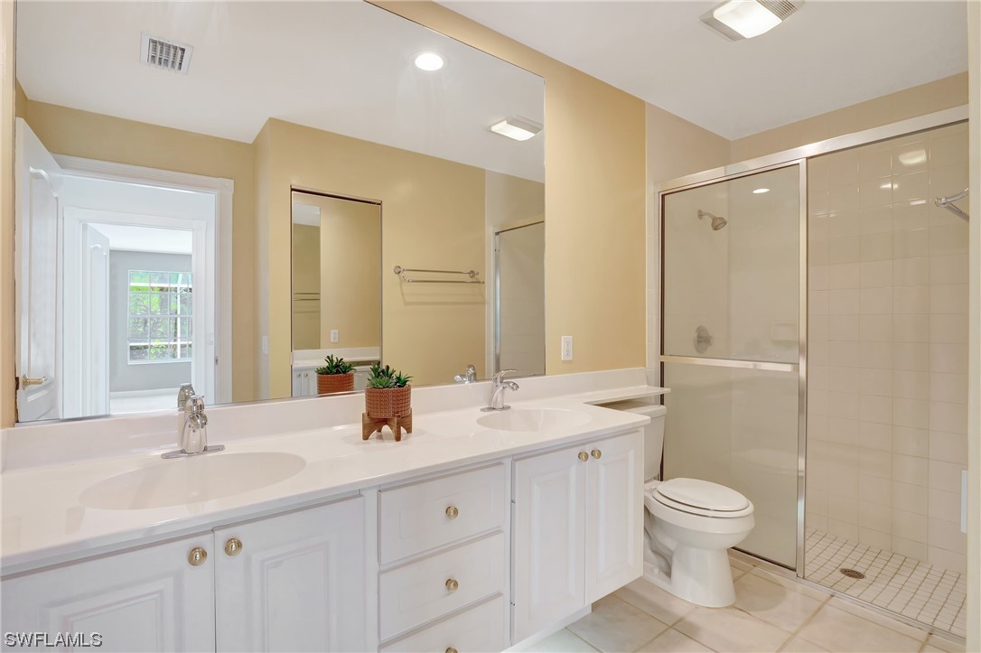 5682 Eleuthera Way Naples, FL 34119 - Photo 9 of 47 a bathroom with a double vanity sink toilet mirror and shower