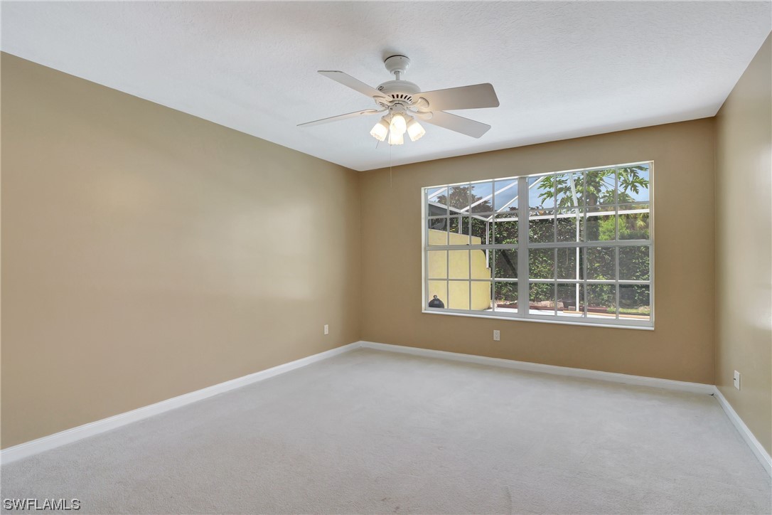5682 Eleuthera Way Naples, FL 34119 - Photo 10 of 47 an empty room with chandelier fan and windows