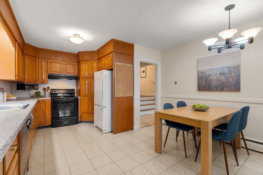 61 Sevland Road Newton, MA 02459 - Photo 8 of 27 a kitchen with a table chairs refrigerator and microwave