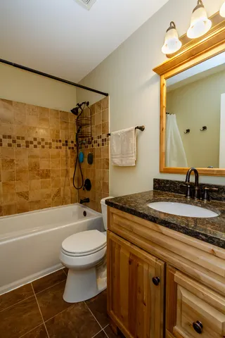 a bathroom with a granite countertop toilet sink and mirror