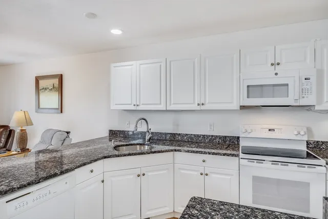 a kitchen with stainless steel appliances granite countertop white cabinets sink and dishwasher