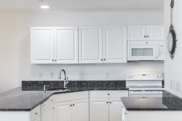 a kitchen with granite countertop white cabinets and stainless steel appliances