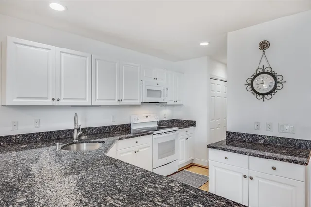 a kitchen with granite countertop a stove a sink dishwasher and cabinets with wooden floor