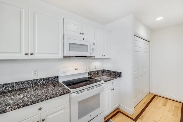 a kitchen with white cabinets and appliances