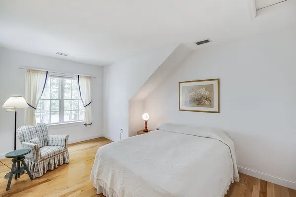 a spacious bedroom with a bed and wooden floor