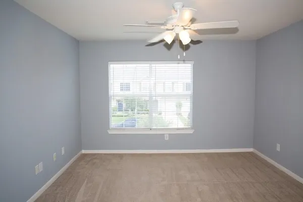 an empty room with a window and a chandelier fan