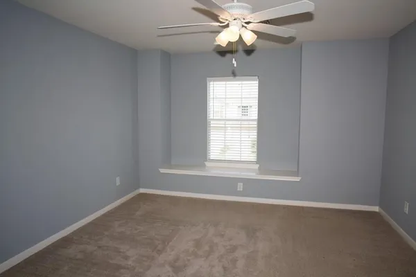 an empty room with a window and a fan